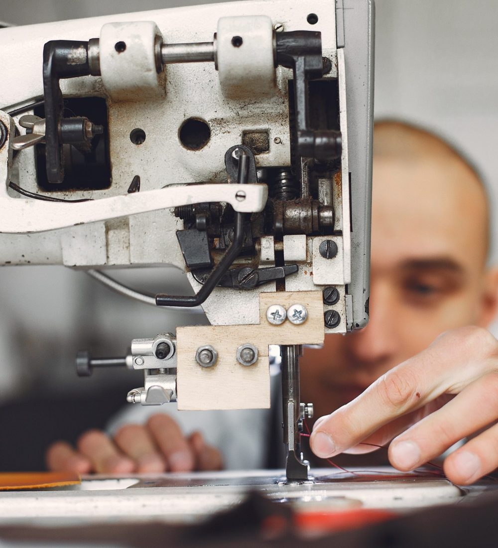 Man working with leather. Professional makes a wallet. Man uses a sewing mashine.
